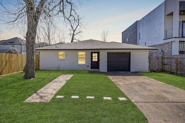 view of front of house with brick siding, a lawn, fence, a garage, and driveway