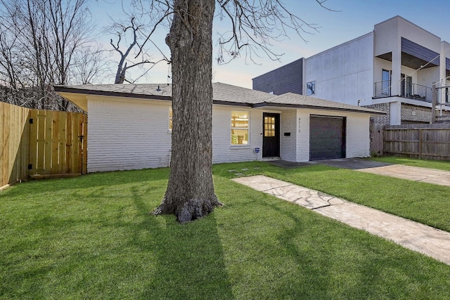 view of front of property featuring concrete driveway, a front lawn, an attached garage, and fence