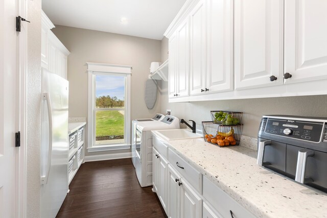 laundry area featuring a sink, baseboards, independent washer and dryer, cabinet space, and dark wood-style floors