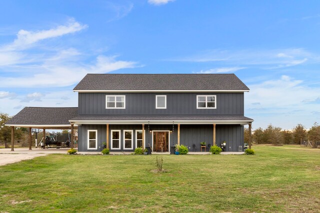 view of front of home with board and batten siding, a shingled roof, a front lawn, and a carport
