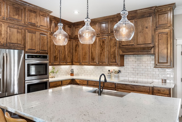kitchen featuring light stone counters, decorative light fixtures, tasteful backsplash, appliances with stainless steel finishes, and a sink