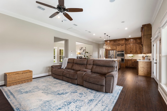 living room with baseboards, visible vents, dark wood finished floors, ceiling fan, and crown molding