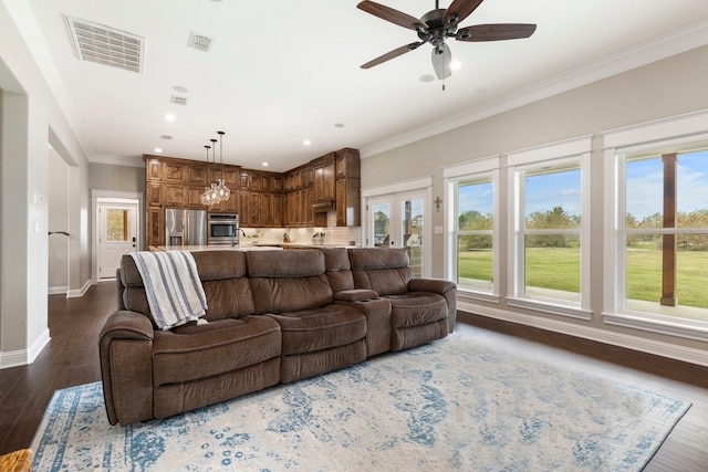living area featuring a wealth of natural light, visible vents, and crown molding