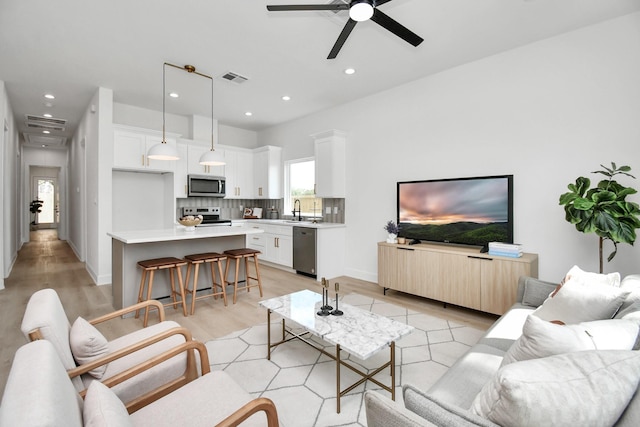 living area with light wood-style floors, recessed lighting, visible vents, and ceiling fan