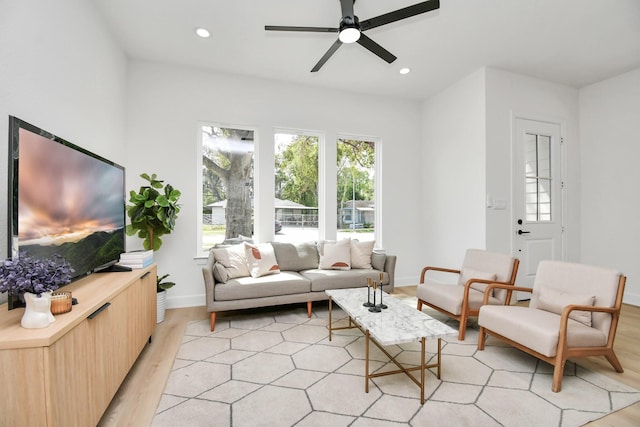 living area featuring baseboards, light wood finished floors, a ceiling fan, and recessed lighting