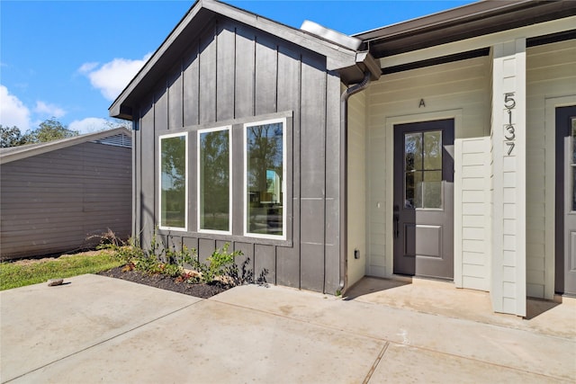 property entrance with board and batten siding and a patio