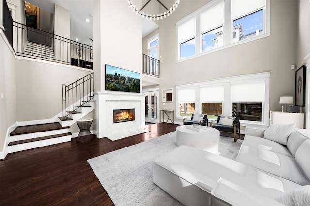 living area featuring stairs, a fireplace, baseboards, and wood finished floors