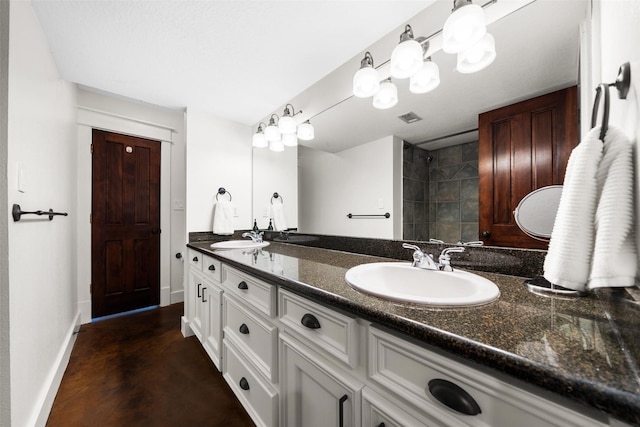 full bath featuring double vanity, baseboards, visible vents, and a sink