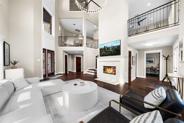 living room with a towering ceiling, a premium fireplace, baseboards, and wood finished floors