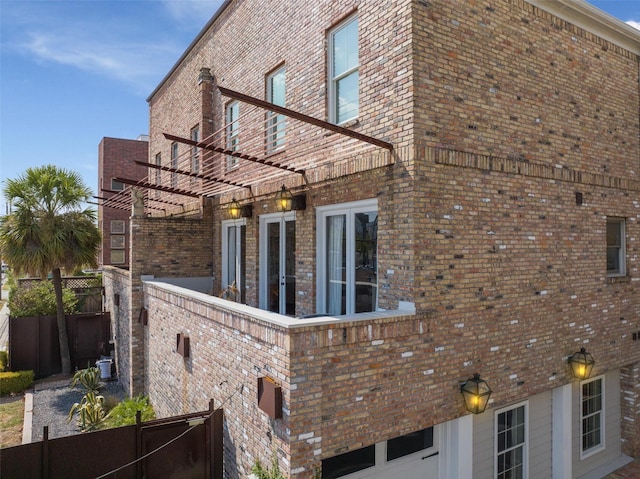 view of home's exterior featuring brick siding, fence, and a pergola