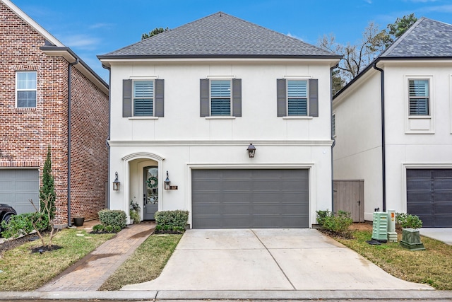 view of front of house featuring driveway, a shingled roof, an attached garage, and stucco siding