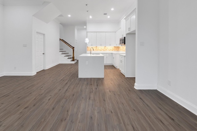 kitchen featuring open floor plan, stainless steel microwave, backsplash, and dark wood-style flooring