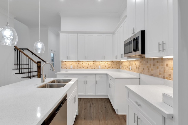 kitchen featuring a sink, white cabinetry, appliances with stainless steel finishes, tasteful backsplash, and decorative light fixtures