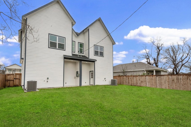 rear view of house with a fenced backyard, central AC, and a yard