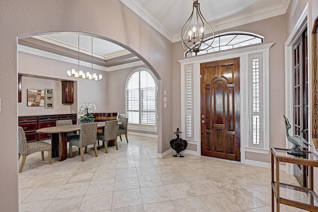 foyer entrance featuring baseboards, ornamental molding, and an inviting chandelier