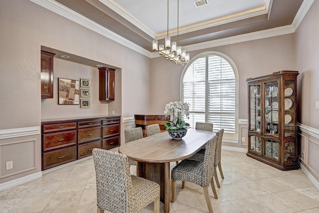 dining area featuring light tile patterned floors, ornamental molding, a raised ceiling, and a decorative wall