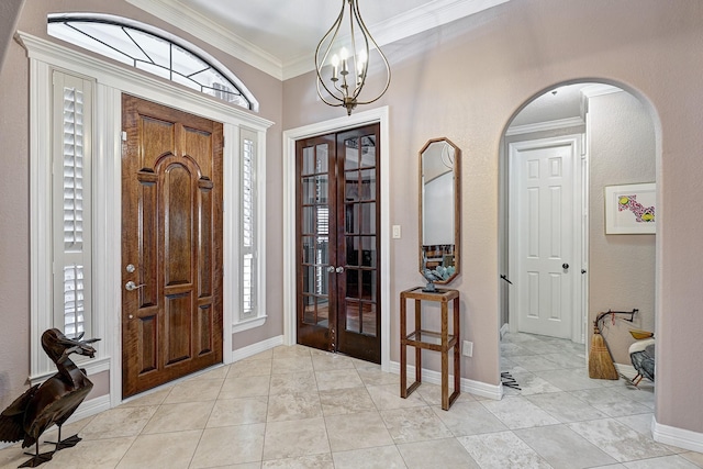 entryway with light tile patterned floors, baseboards, arched walkways, and crown molding