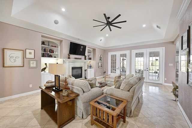 living room featuring light tile patterned floors, a raised ceiling, a glass covered fireplace, french doors, and built in shelves