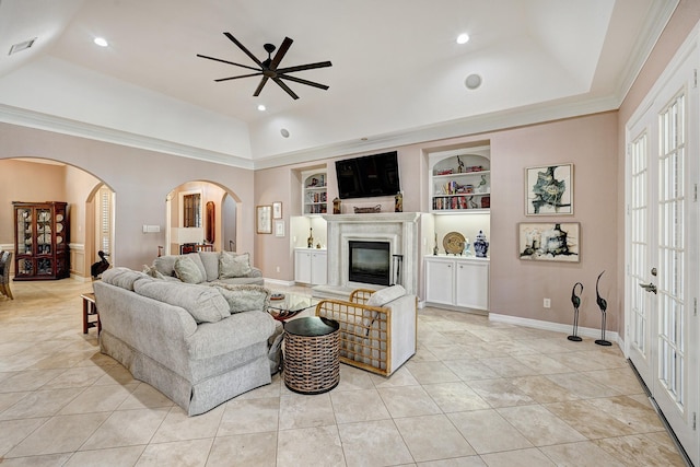 living area featuring arched walkways, a fireplace, visible vents, built in features, and a raised ceiling