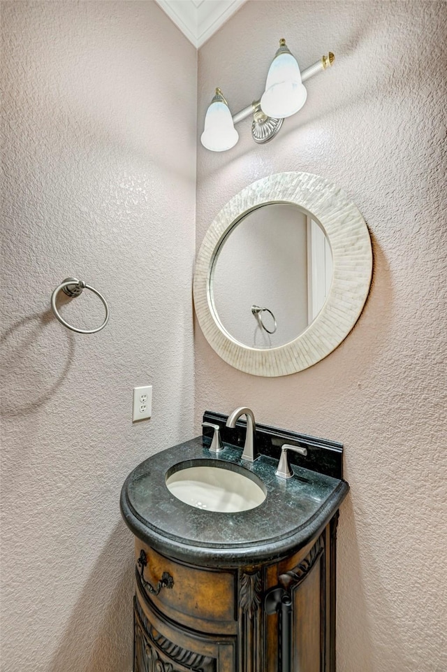 bathroom featuring a textured wall, ornamental molding, and vanity