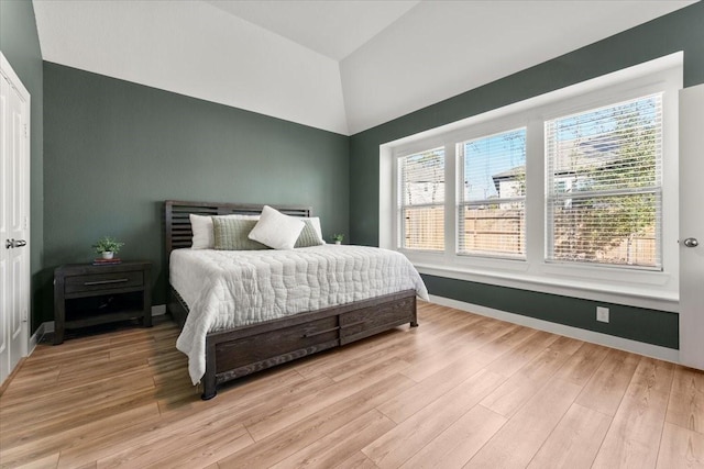 bedroom with lofted ceiling, light wood-style flooring, and baseboards