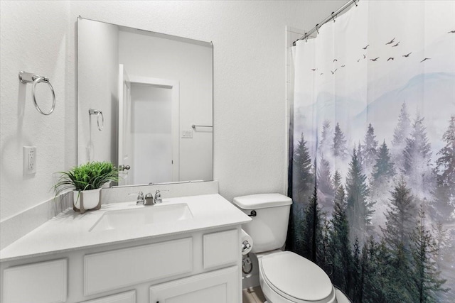 full bath featuring a shower with shower curtain, a textured wall, vanity, and toilet