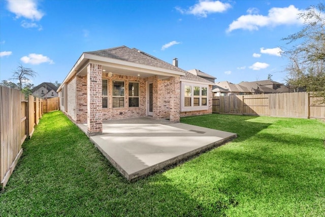 back of property with a patio, brick siding, a lawn, and a fenced backyard