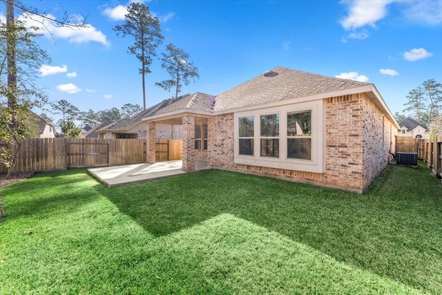 rear view of property featuring a patio, a fenced backyard, central AC, brick siding, and a yard