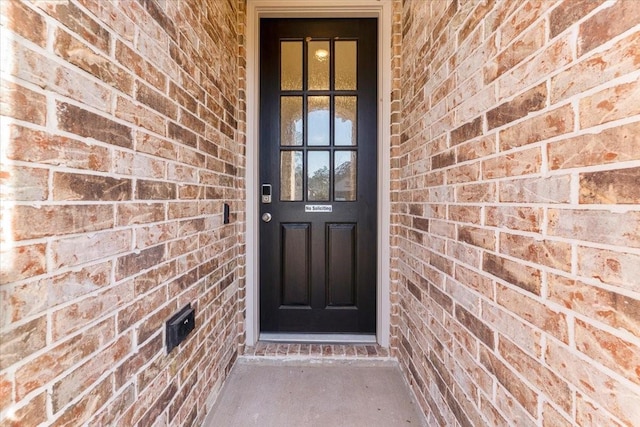 view of exterior entry featuring brick siding