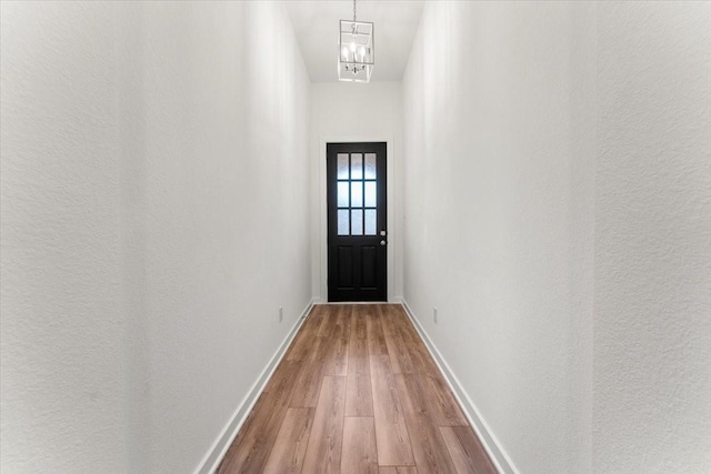 entryway featuring an inviting chandelier, baseboards, and wood finished floors