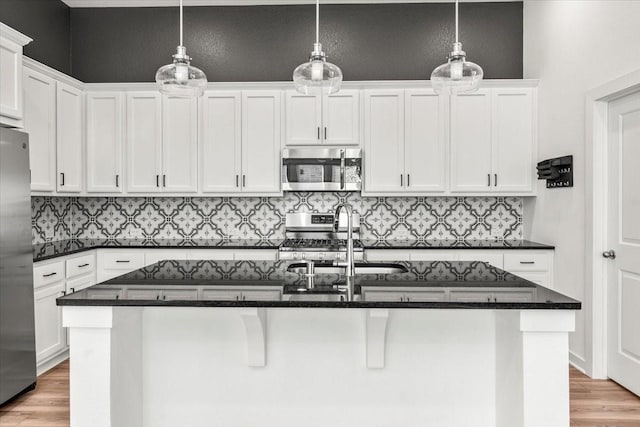 kitchen with appliances with stainless steel finishes, light wood-style floors, white cabinets, and a sink