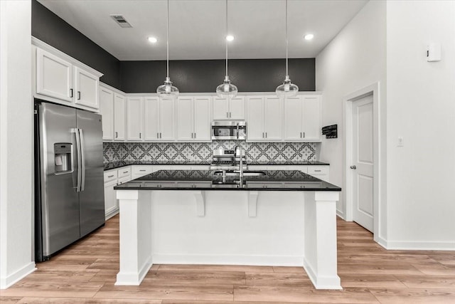 kitchen with stainless steel appliances, visible vents, white cabinetry, light wood-type flooring, and decorative light fixtures