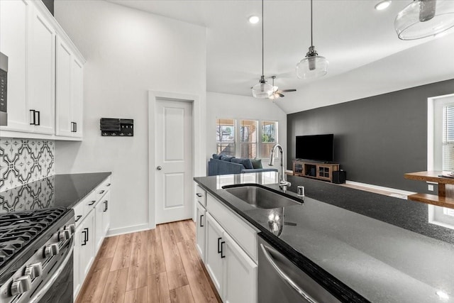 kitchen featuring a sink, white cabinets, appliances with stainless steel finishes, decorative backsplash, and light wood finished floors