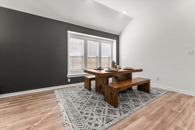 dining room featuring baseboards, vaulted ceiling, and light wood finished floors