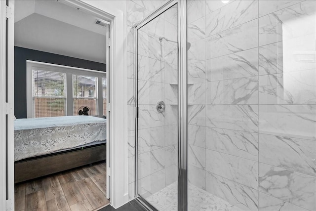 ensuite bathroom with connected bathroom, a shower stall, and wood finished floors