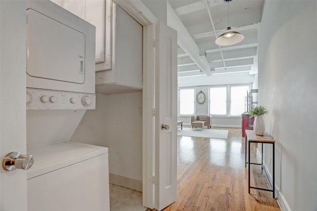 laundry room with baseboards, laundry area, stacked washing maching and dryer, and light wood-style floors