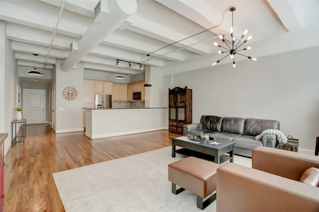 living room with an inviting chandelier, light wood-style flooring, baseboards, and beam ceiling