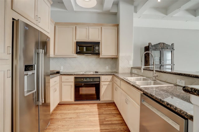 kitchen with cream cabinetry, tasteful backsplash, light wood-style flooring, a sink, and black appliances