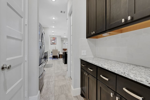 kitchen featuring light stone counters, recessed lighting, visible vents, dark brown cabinets, and backsplash