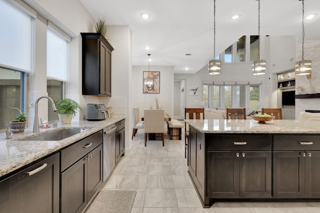 kitchen featuring pendant lighting, open floor plan, a sink, and light stone countertops