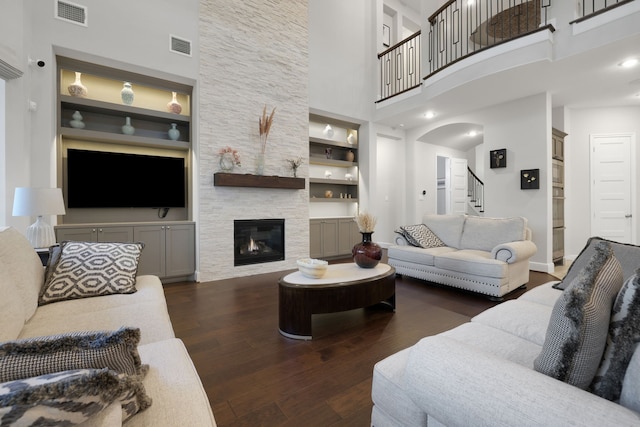 living area with a fireplace, wood finished floors, visible vents, and built in features