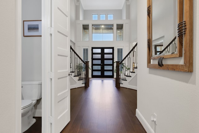 entryway featuring dark wood-style floors, stairway, a towering ceiling, and baseboards