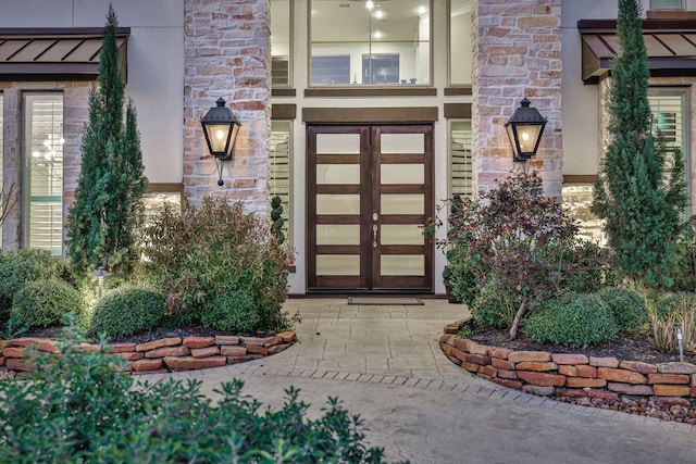 doorway to property featuring stone siding, metal roof, a standing seam roof, french doors, and stucco siding