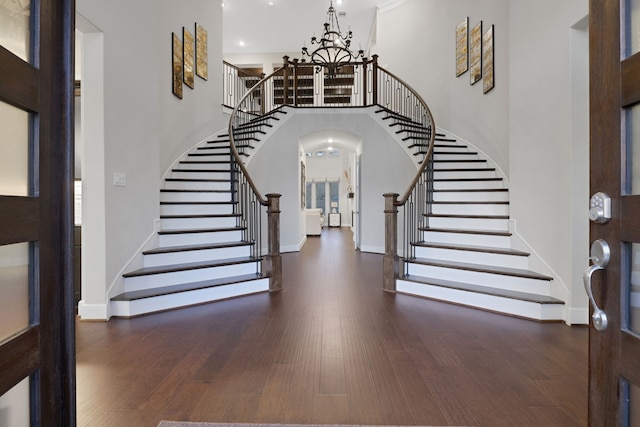 foyer entrance with a chandelier, stairs, a high ceiling, and wood finished floors