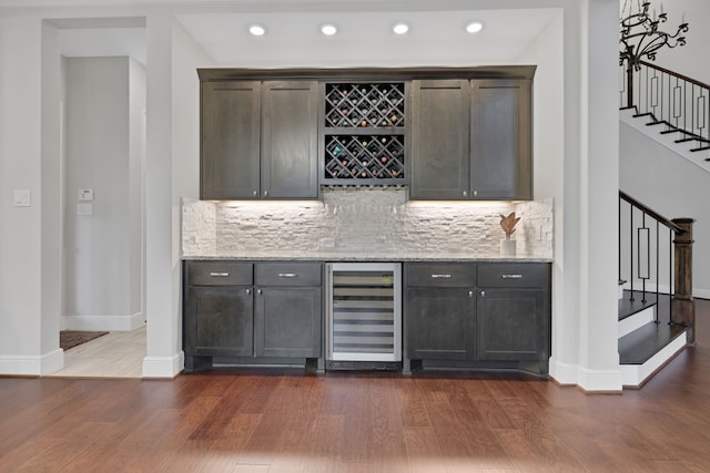 bar with a dry bar, dark wood finished floors, decorative backsplash, wine cooler, and stairs