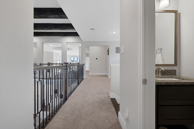 hallway featuring carpet floors, baseboards, and a sink