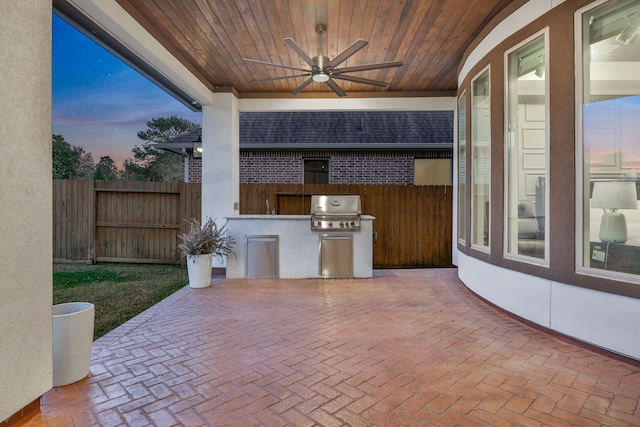 patio terrace at dusk featuring a ceiling fan, fence, grilling area, and area for grilling