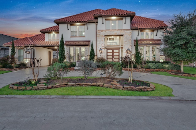 mediterranean / spanish home featuring stone siding, a tile roof, concrete driveway, and stucco siding