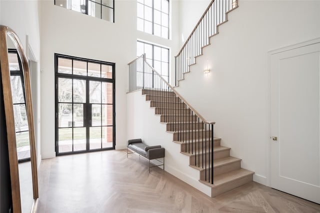 foyer featuring a towering ceiling, stairs, and baseboards