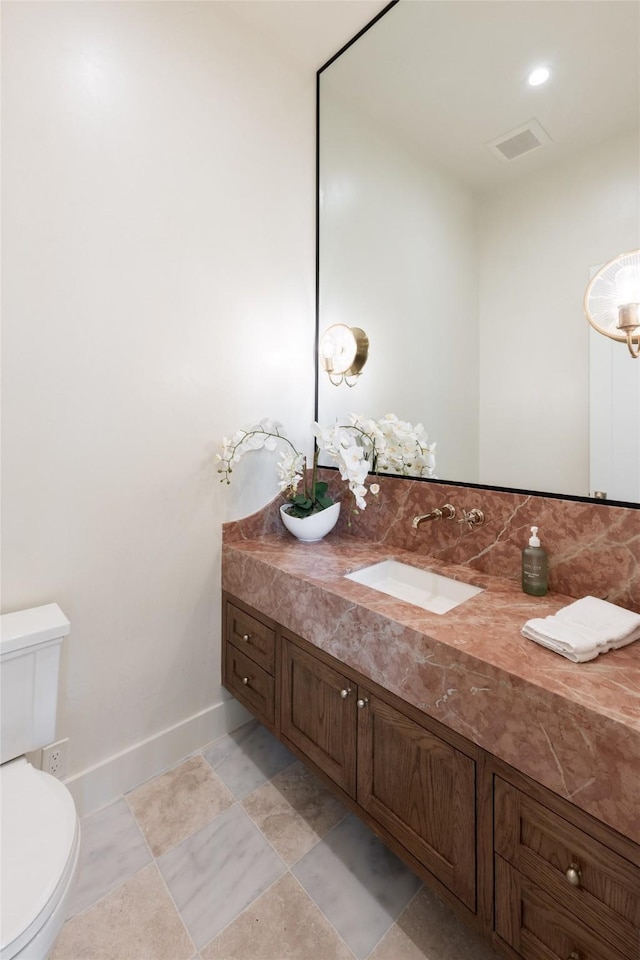 bathroom featuring baseboards, visible vents, vanity, and toilet